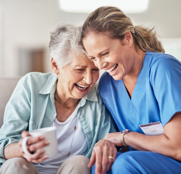 A nurse and an elderly person sitting on a couch.