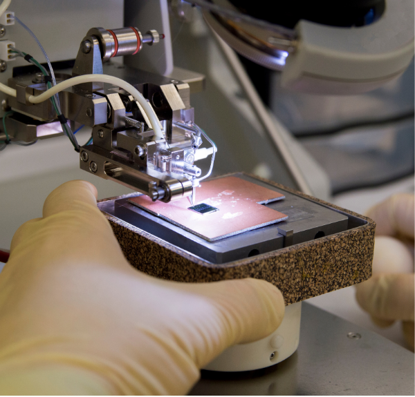 A person working on an electronic device with gloves on.