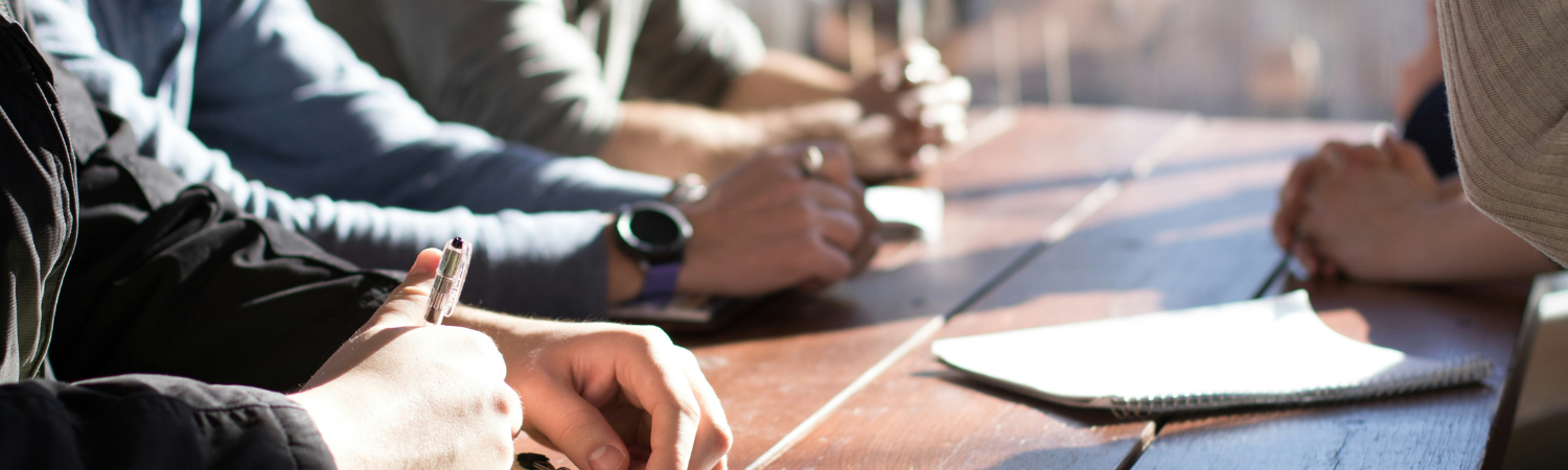 People sitting at a table writing on paper.