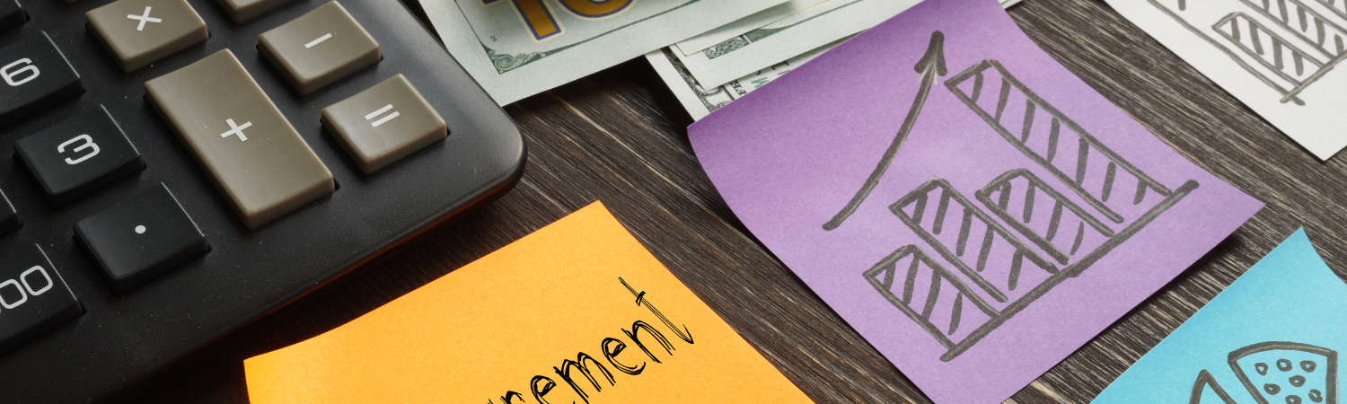 Post-it note next to post-it note with calculator on wooden desk.