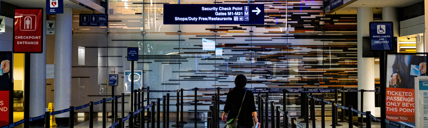 View of an airport security area featuring a passenger walking in line.