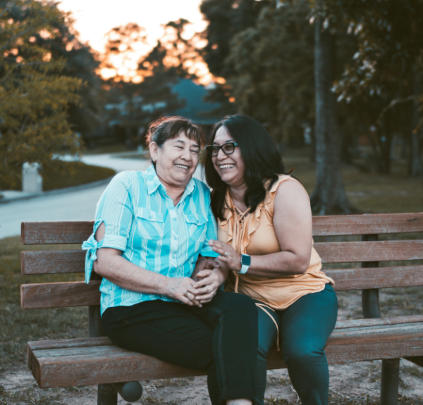 Two older adults sitting on a bench.